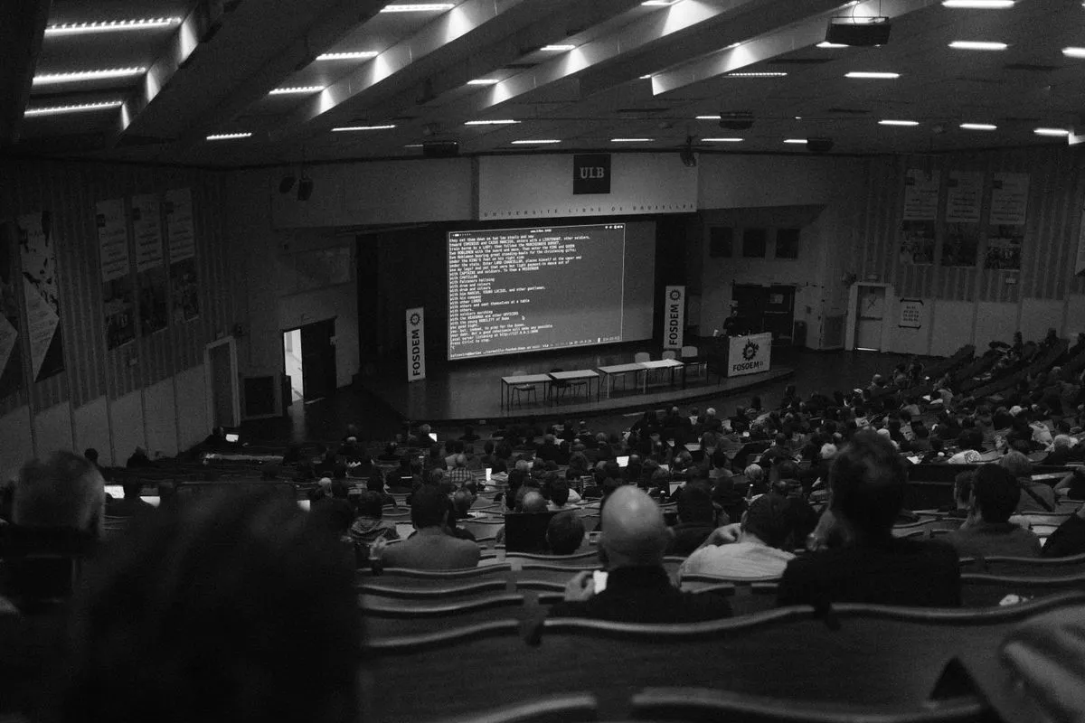 Plateia em preto e branco assistindo a uma palestra técnica em um auditório